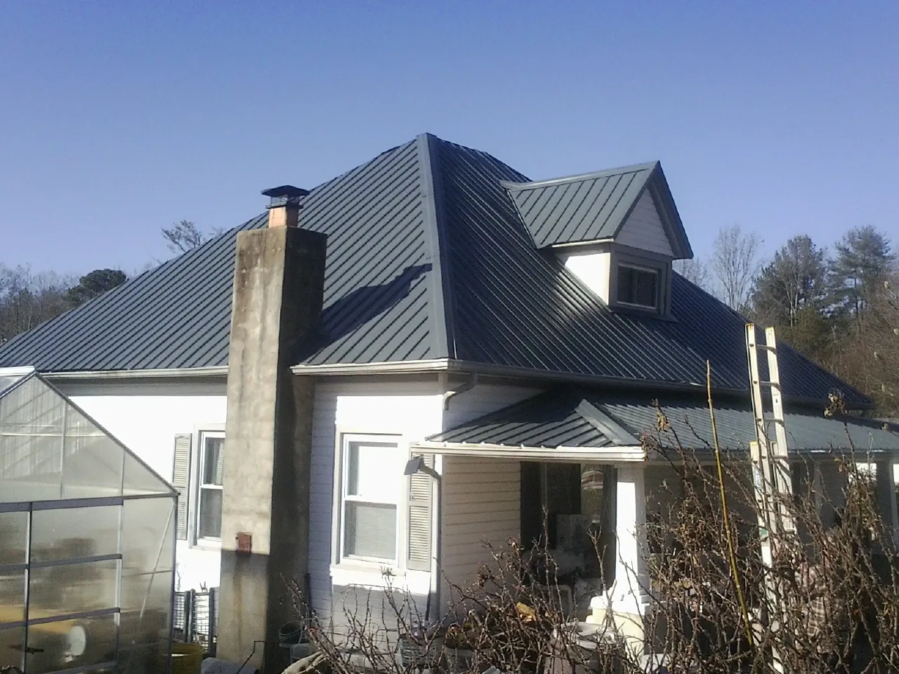 Dark blue standing seam metal roof on a white farmhouse with dormer — Slate & Tile Roof Repair by Roofing Brothers in Sweet Home