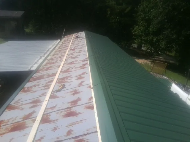 Old rusted panels beside newly installed green metal roofing — Wind Damage Roof Repair by Roofing Brothers in Sweet Home