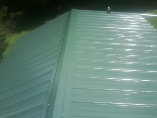New green metal panels meeting at the ridge of a roof — Flat Roof Repair work by our crew in Sweet Home