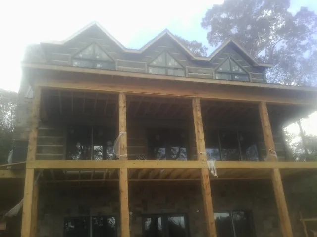 Dormers and porch framing on a large log home under construction — Roof Coating work by our crew in Sweet Home