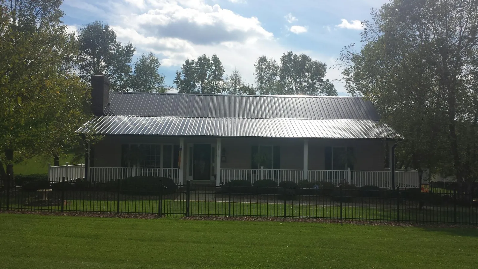 Gray metal roof on a brick ranch with a full width front porch — Gutter Guard Installation work by our crew in Sweet Home