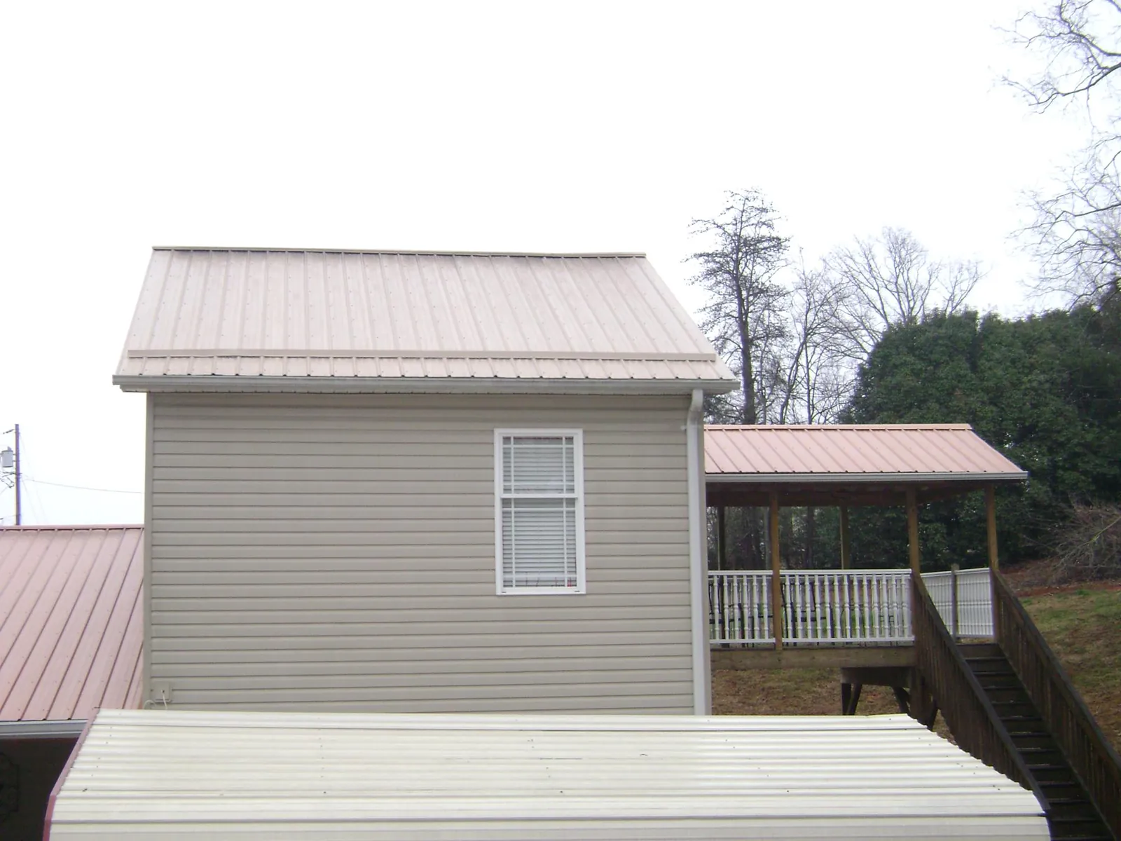 Tan metal roofs on a two story addition and attached porch, from a Roof Replacement job in Sweet Home