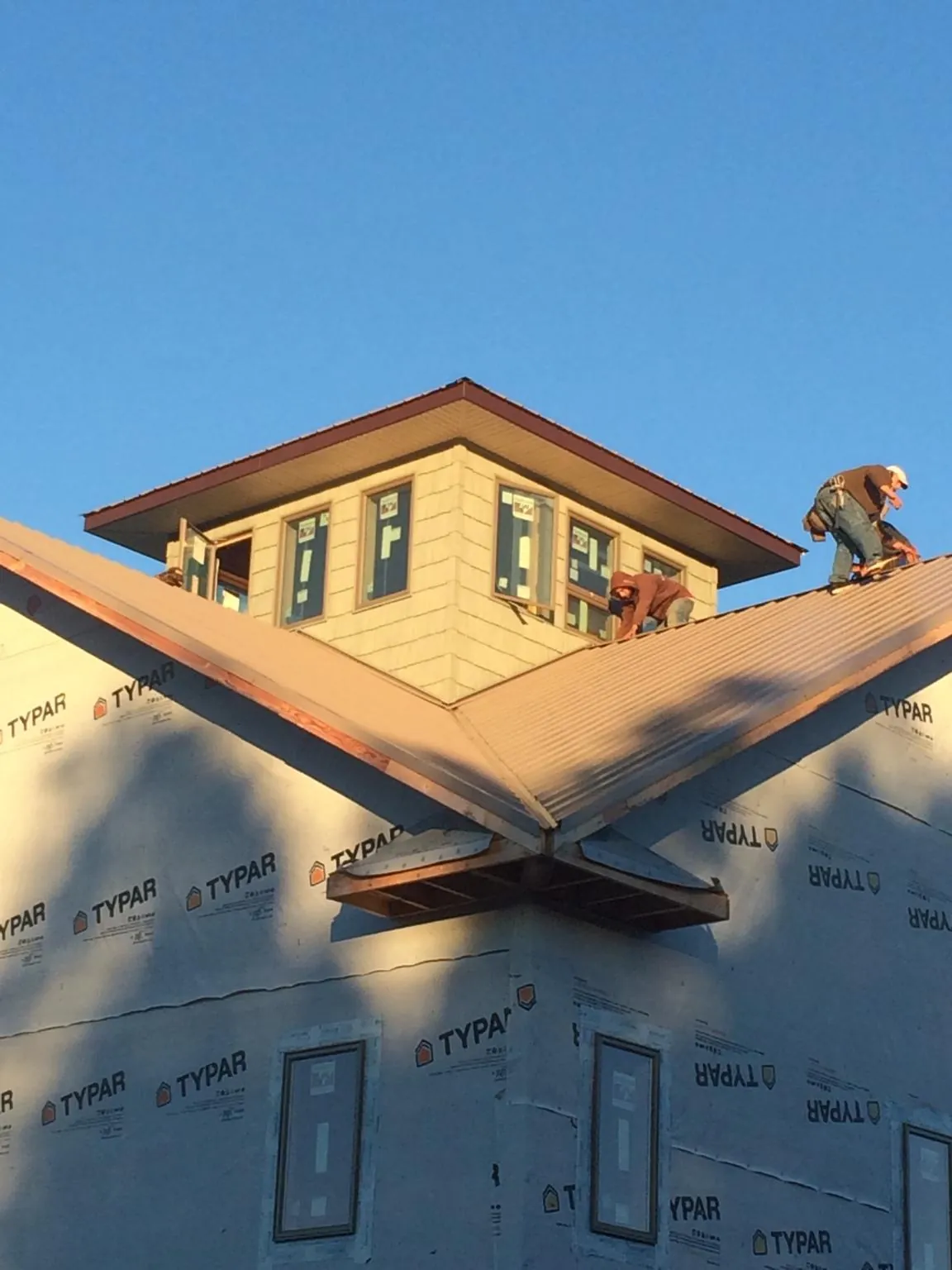Roofers working around a rooftop cupola on a new metal roof at sunset — Roof Waterproofing in Sweet Home by Roofing Brothers